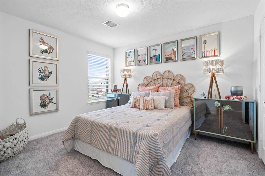 Secondary bedroom features plush carpet, custom paint, light, ample closet space, and a large window with privacy blinds.