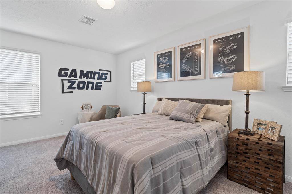Secondary bedroom features plush carpet, custom paint, light, ample closet space, and a large window with privacy blinds.