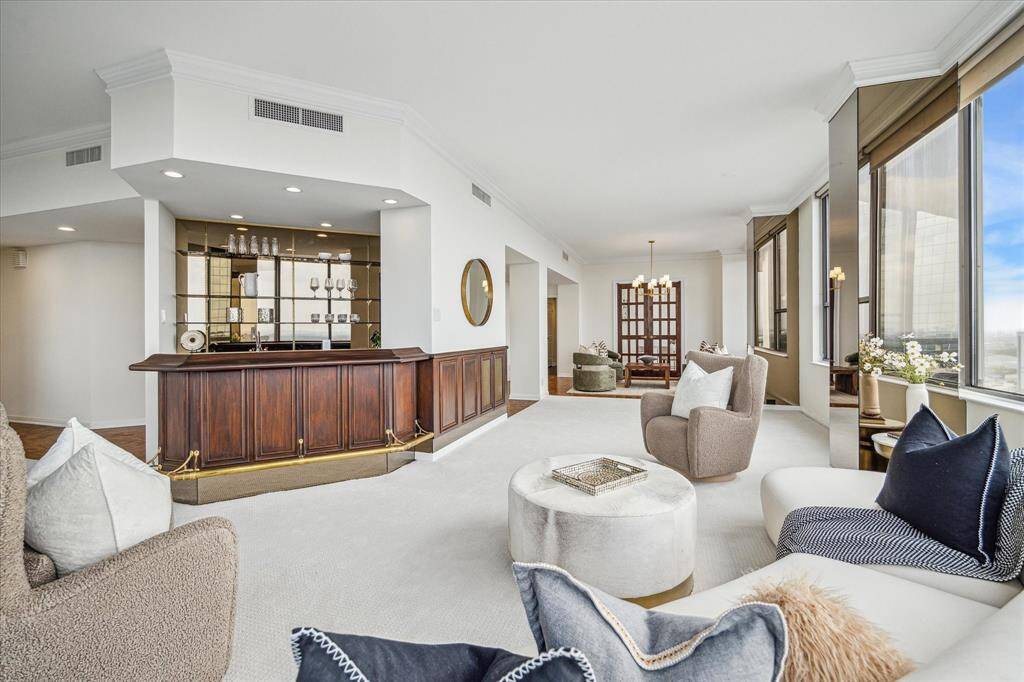 Anchoring the living area is the custom wood panel and brass accent wet bar with ice-maker and mirrored feature wall with shelving to display favorite items or barware. Under-bar storage for glassware and mixing accoutrement. Staging shown no longer in residence.
