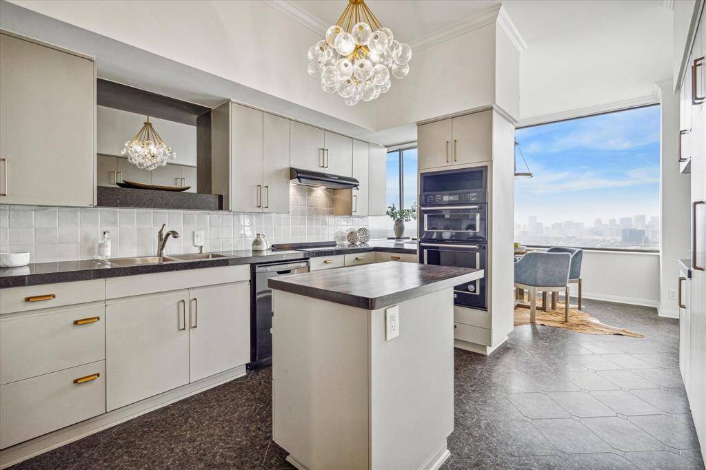Well-equipped kitchen with electric cooktop and dual oven, warming drawer, dishwasher, paneled refrigerator, prep island, and wonderful custom storage.