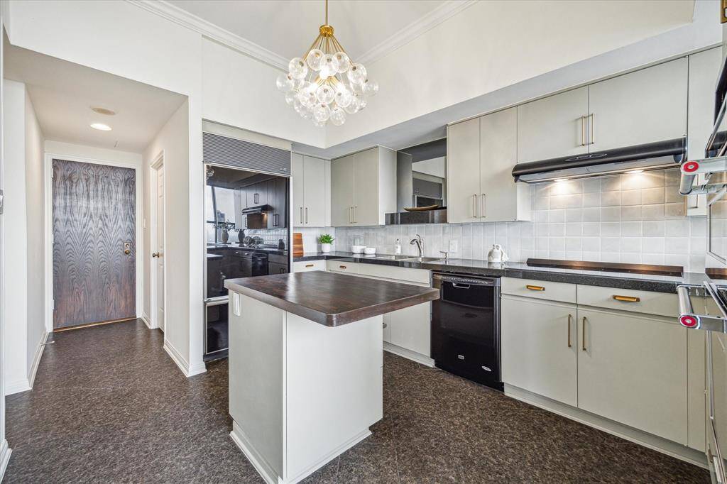 Another view of the kitchen. At back left is the secondary "back door" to residence, with door to laundry room at right. Note the paneled refrigerator, washer, and dryer convey with the property.