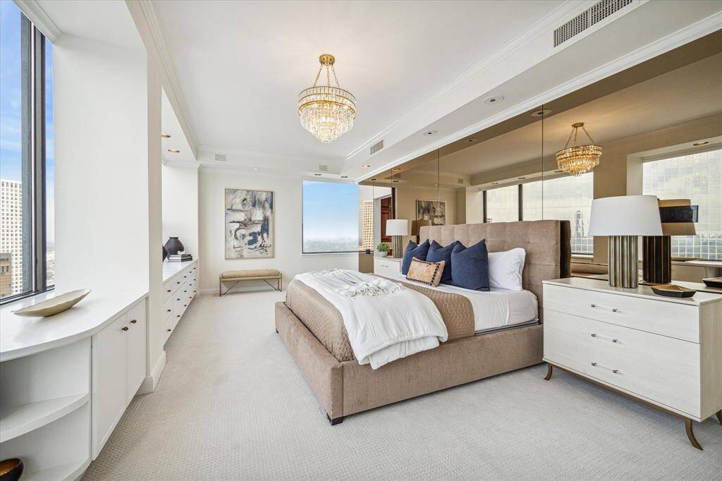 Impressively large, airy primary bedroom with bronze-mirrored feature wall, glimmering crystal chandelier, recessed ceiling, and those incredible views! Staging shown no longer in residence.