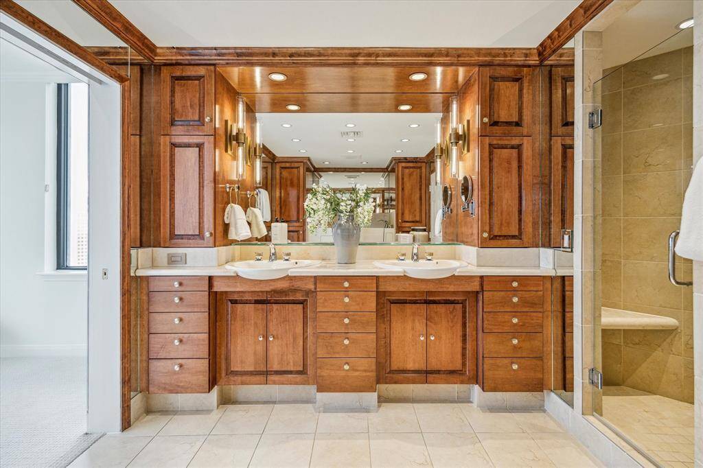 Elegant wood-paneled primary vanity with dual sinks and refined dual-sconce and recessed lighting.