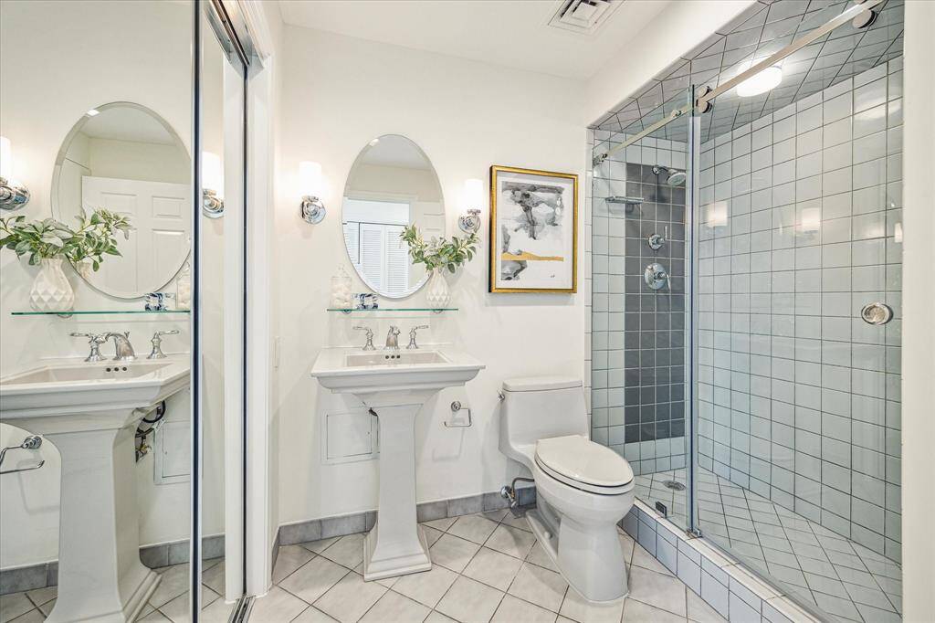 Nicely appointed guest bath with new pedestal sink and commode; mirrored closet at left.