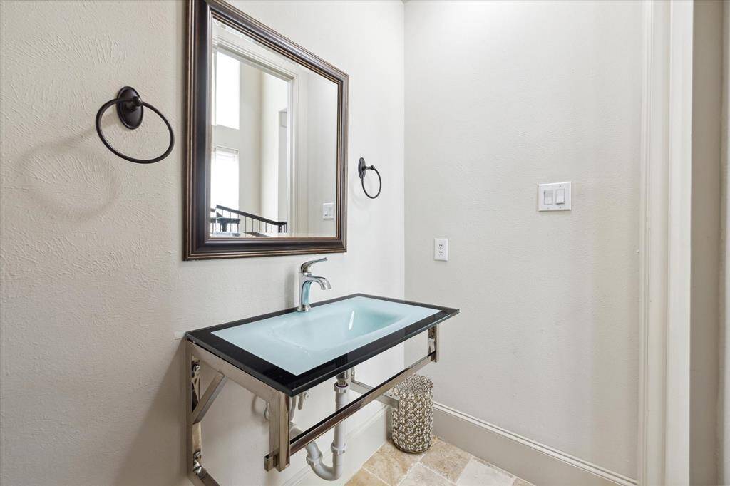 This spacious half bath, equipped with a framed mirror and a distinctive sink, serves the first floor.