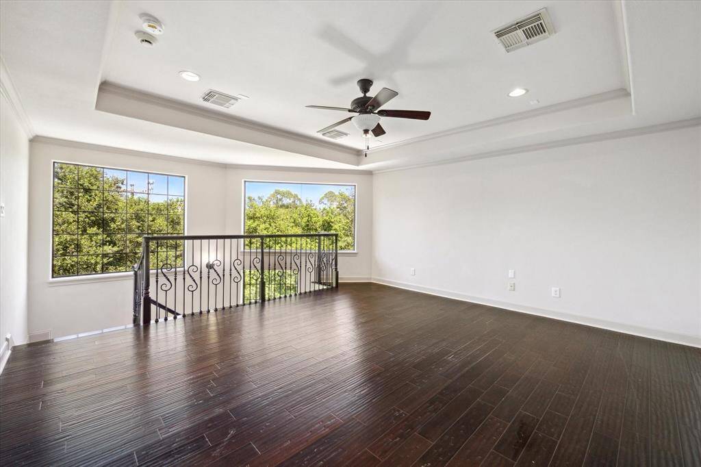 The game room on the third floor boasts a tray ceiling, beautiful, wood flooring, and breathtaking windows that offer stunning views of the backyard, pool, and spa.