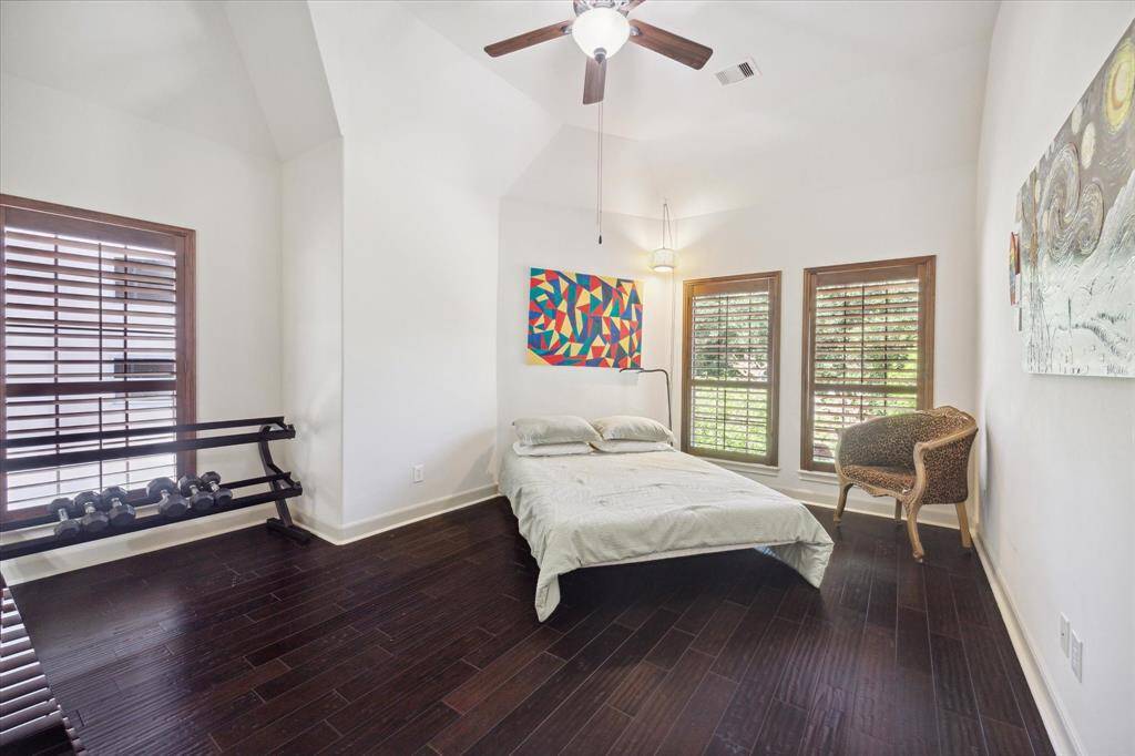 The secondary bedroom boasts large windows, a ceiling fan with light, high ceiling, beautiful wood flooring, a walk-in closet, and a Hollywood bath.