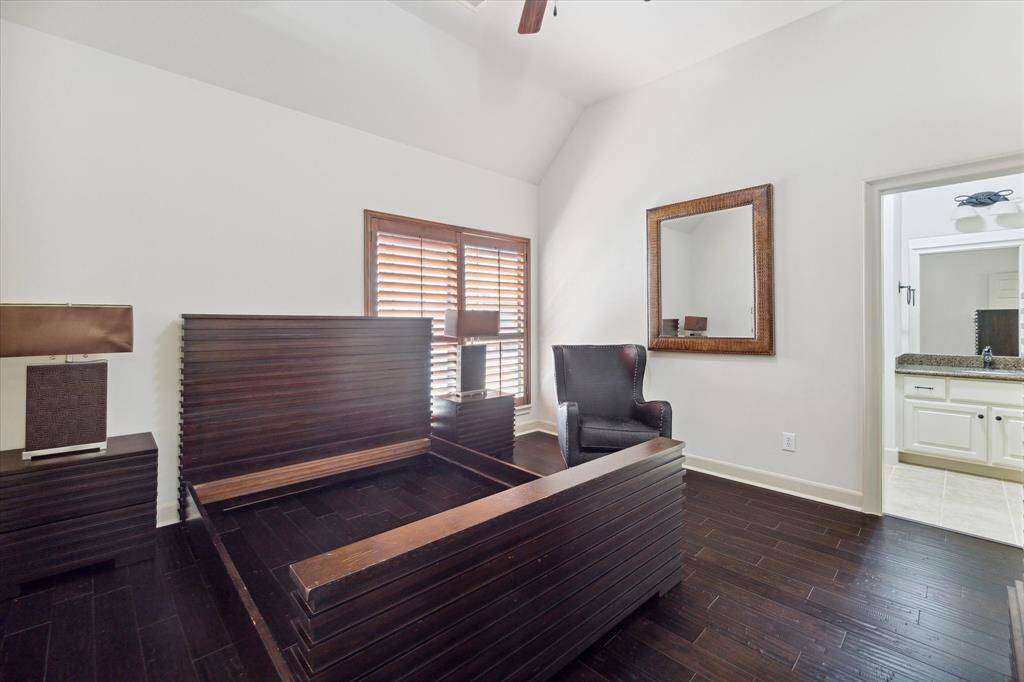 The secondary bedroom features a high ceiling with fan and light, wood flooring, a walk-in closet, and a Hollywood bath.