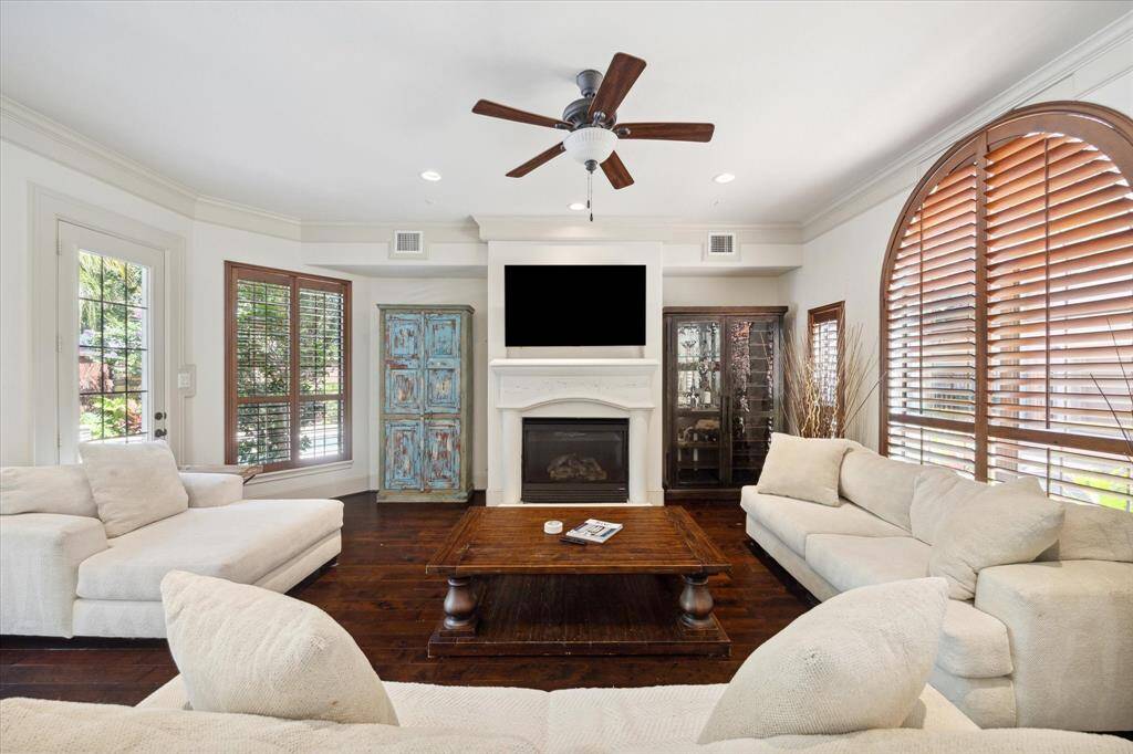The living area is well designed and well lit and boasts crown molding, gorgeous wood flooring, a ceiling fan with light, recessed lighting, a gas fireplace with an elegant surround and mantle, and a door opening to the backyard pool and spa.