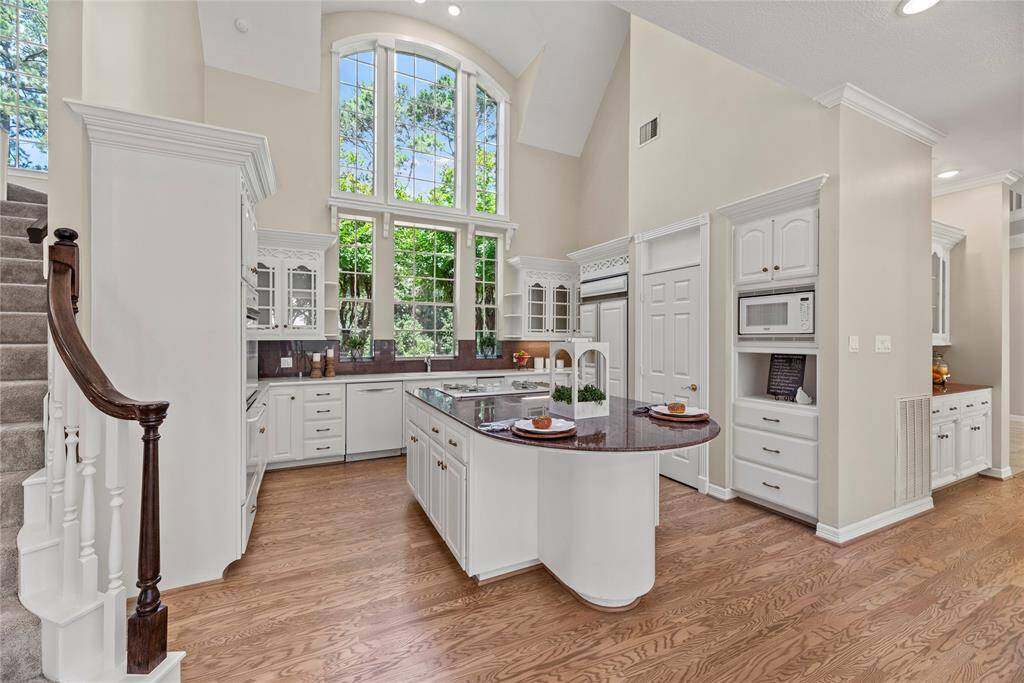 This stunning space features a wall of windows that flood the room with natural light, a large island perfect for entertaining, gleaming granite countertops, double ovens, a gas cooktop for the gourmet chef, and elegant glass front cabinetry.