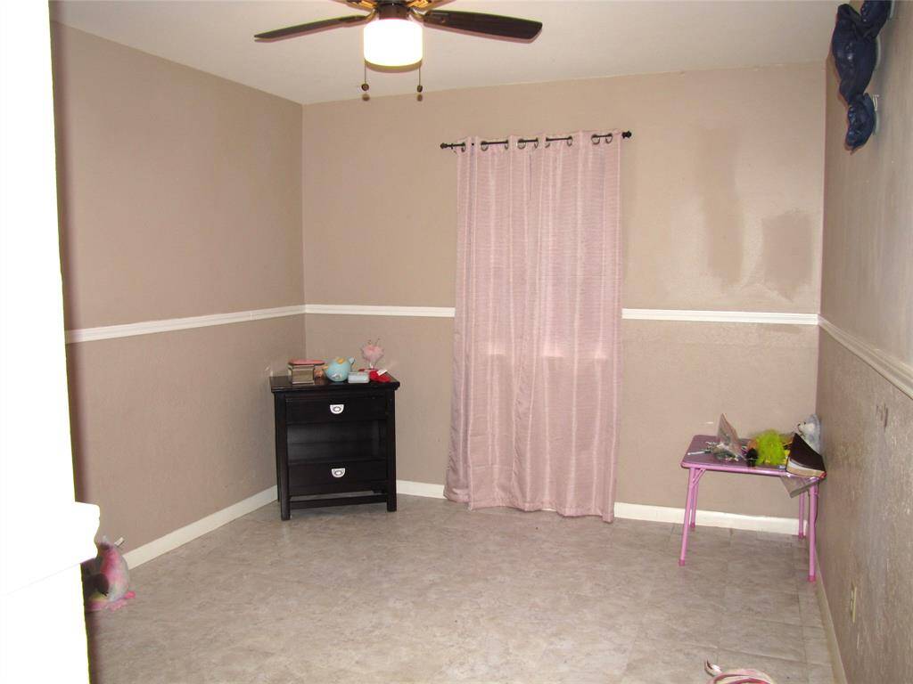 One of the secondary bedrooms featuring neutral walls, chair rail molding, a ceiling fan, and a window to bring in the natural light.