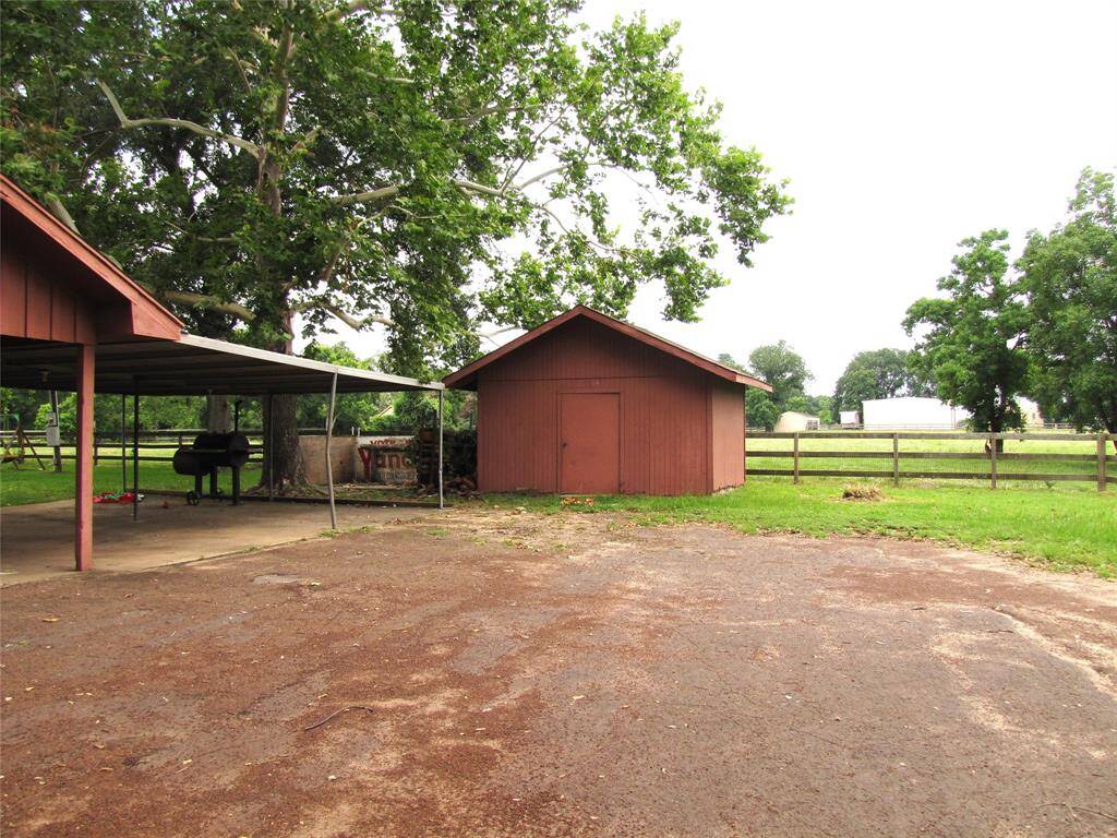 A storage shed stands amidst a rural backdrop, perfect for housing tools and equipment for lawn maintenance and outdoor activities.