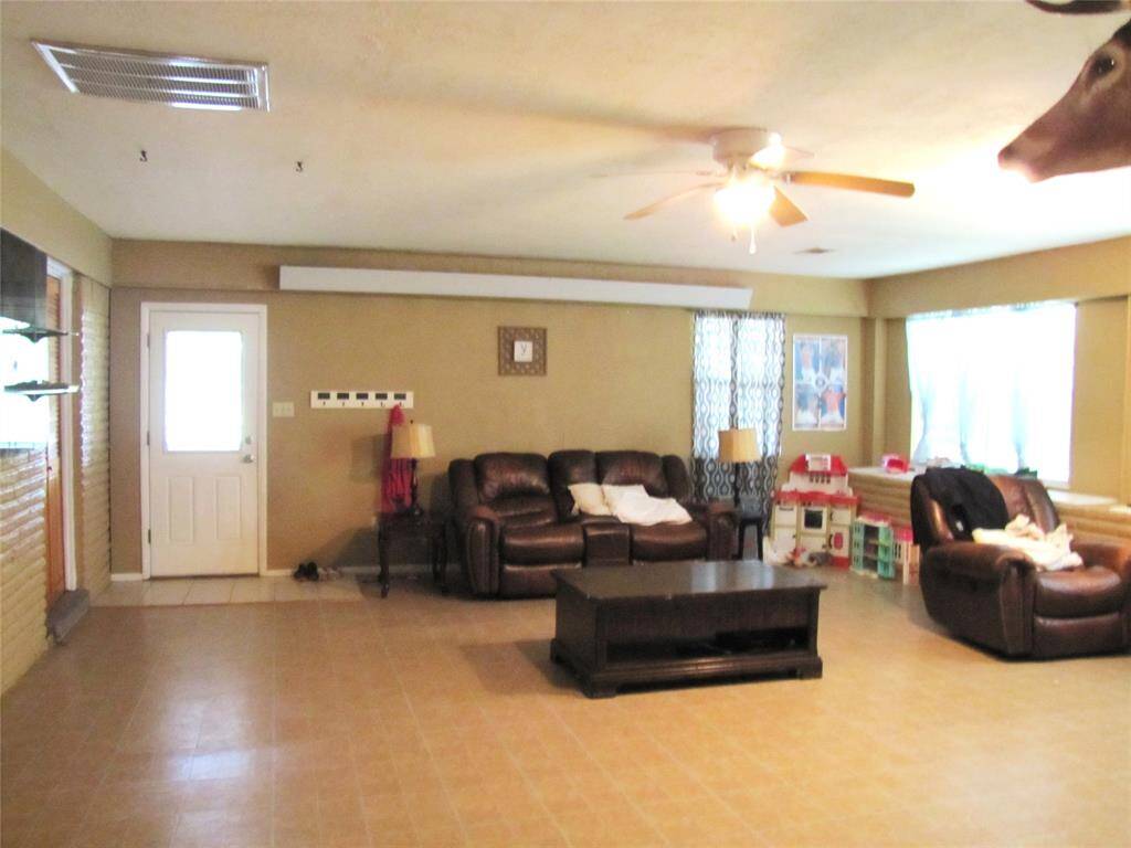 A large den with ample space, tiled floors, and natural light flowing through windows, giving a cozy yet spacious feel.