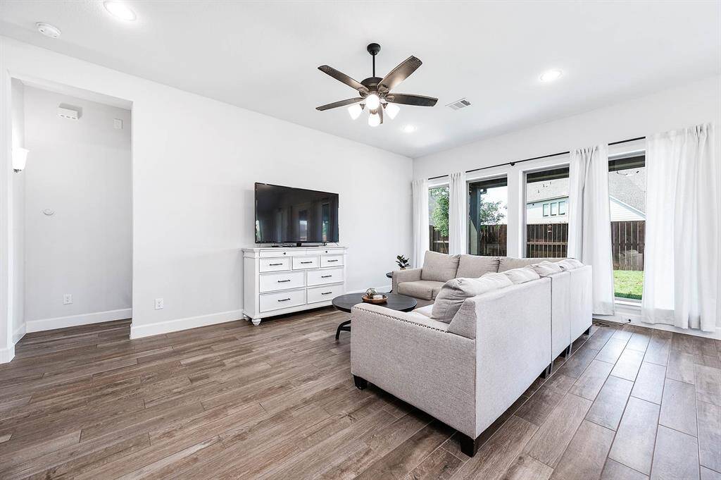 The family room features nice windows that let in plenty of natural light and a whole wall perfect for hanging a large TV, making it an ideal spot for relaxation and entertainment.
