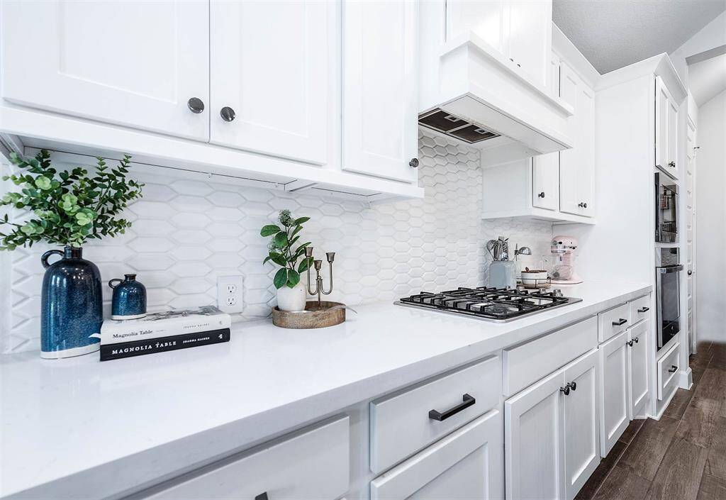 The kitchen features stunning quartz countertops, a beautiful backsplash, and built-in cooktop and stove appliances. This elegant and functional design enhances the cooking experience while adding aesthetic appeal to the space.