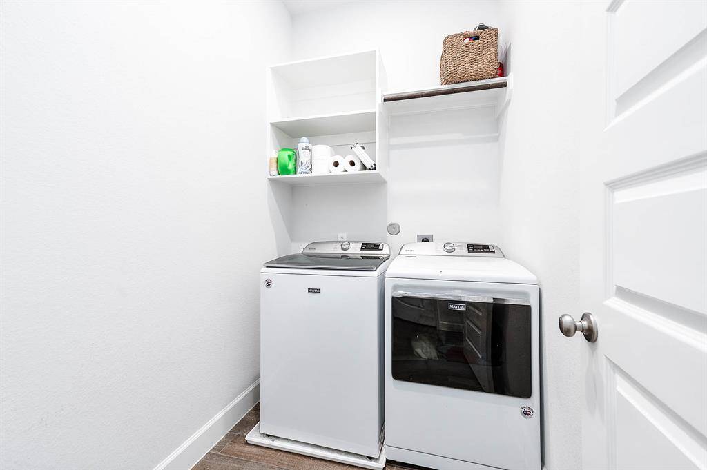 The utility room is conveniently located next to the kitchen, complete with shelving and a pole for hanging clothes. This setup provides practical storage solutions and easy access to laundry essentials, enhancing the functionality of the home.