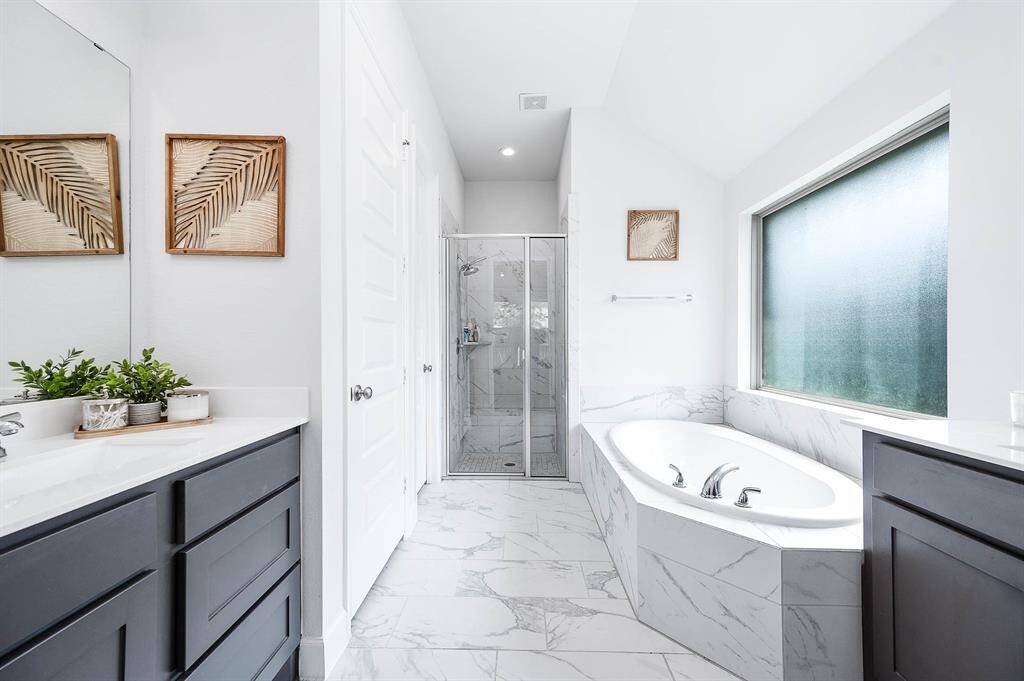 Another tranquil spot is the master bath, featuring a stand-up shower and a garden tub, complemented by his and her sinks. This luxurious setup offers a peaceful retreat within the home.
