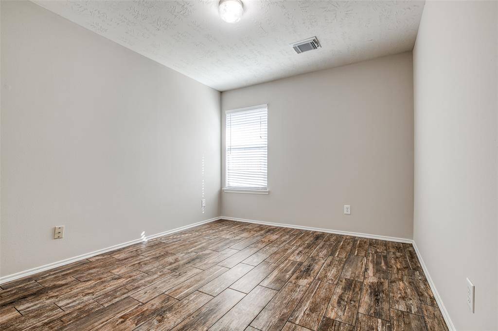 Guest bedroom with wood look tiled flooring to the left of the guest bathroom.