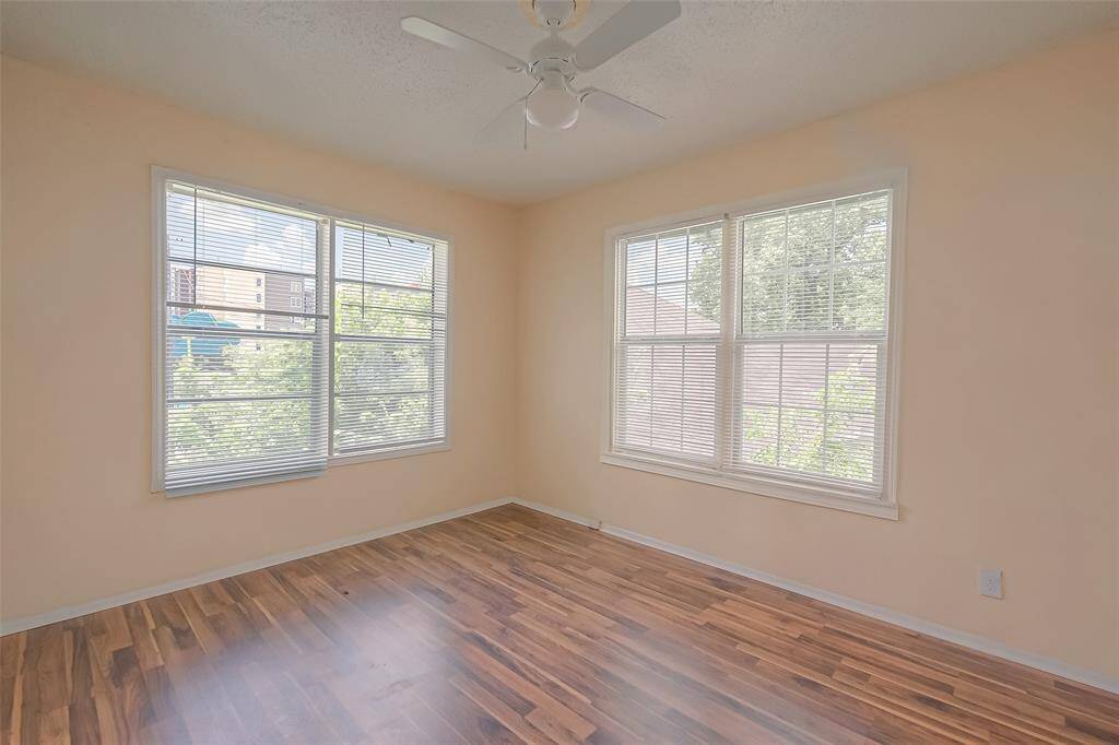 The second bedroom features a ceiling fan and large windows. Ready for your personal touch.
