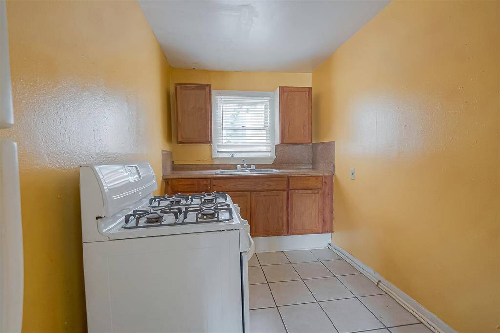 The kitchen features sleek countertops, a gas stove and ample storage space.