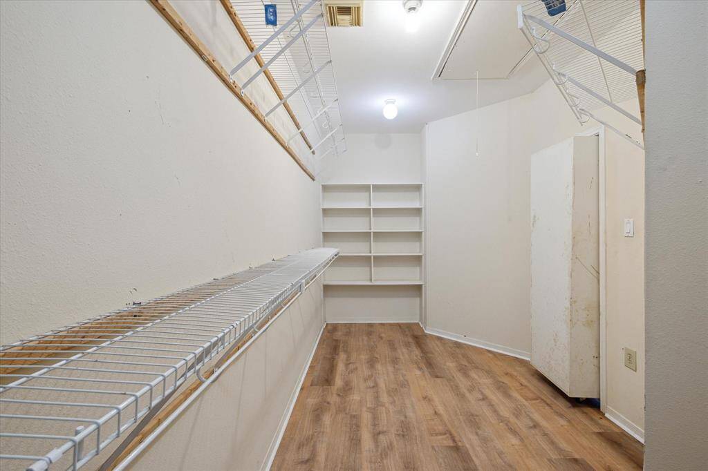 This is a hidden walk-in closet with wire shelving on one side, built-in shelves on the other, and a cabinet in the corner.