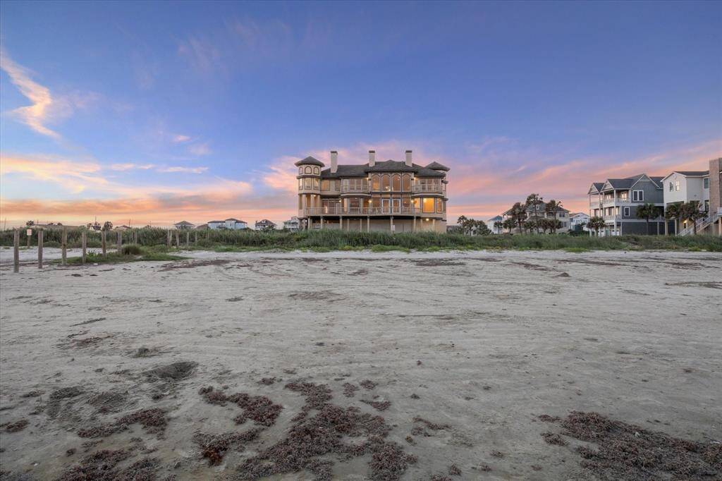 A large, elegant one of a kind beachfront house at twilight with a colorful sky,