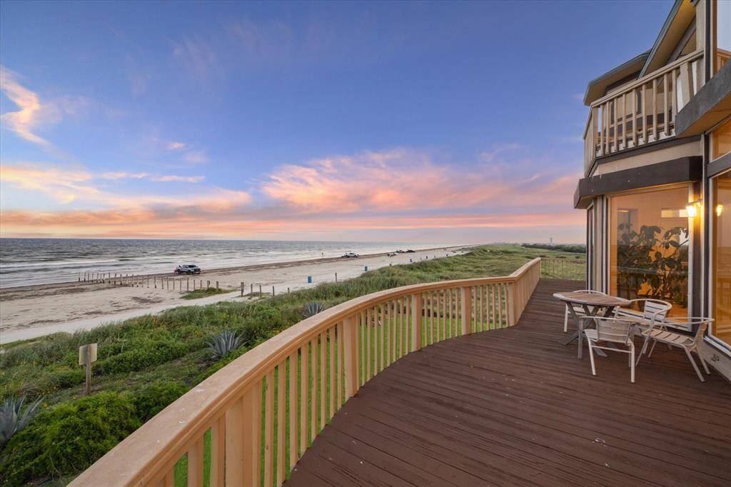 Beachfront house deck at sunset with colorful sky, overlooking a sandy beach with the migrated birds going through Galveston State park.