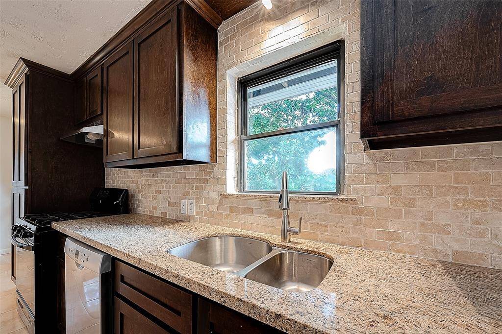 BEAUTIFUL CUSTOM TILE BACKSPLASH, GRANITE COUNTERS, AND STAINLESS STEEL DOUBLE SINK.