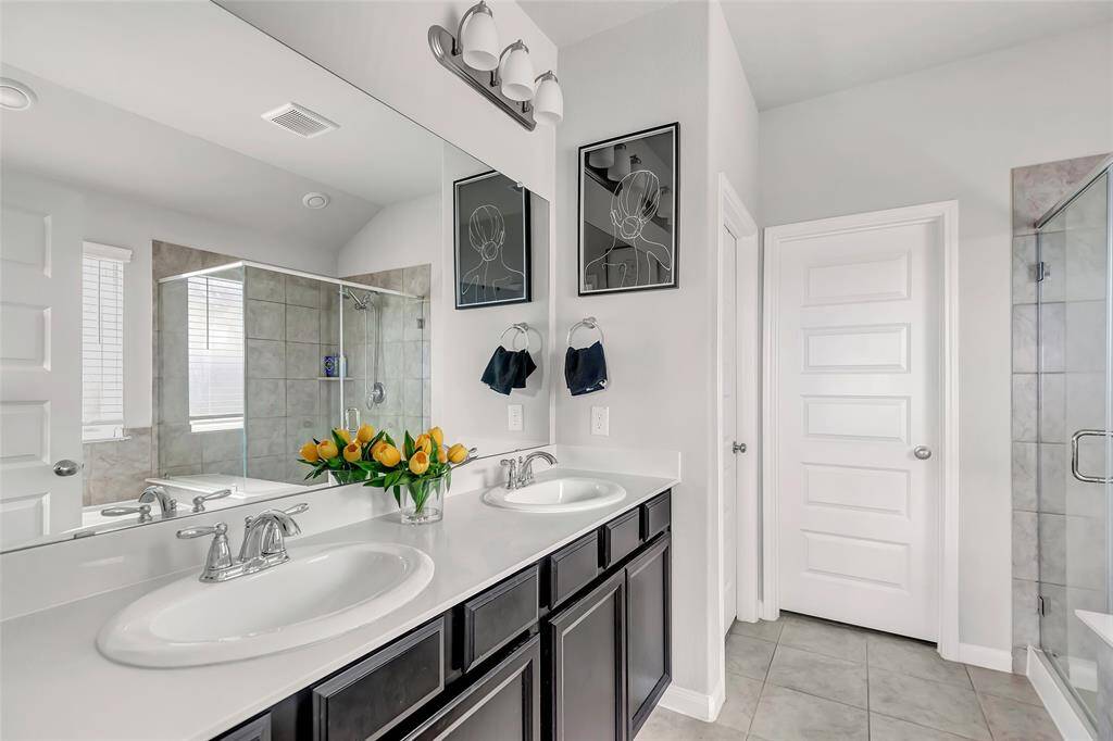 Primary bathroom with double vanities, separate tub, and shower.