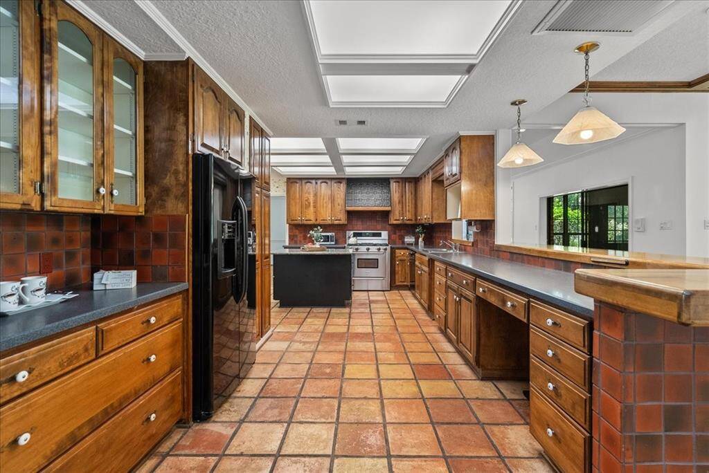 Indulge in the functionality of this kitchen, boasting a convenient desk area, sleek glass cabinetry, and storage galore, exceeding your every organizational need.