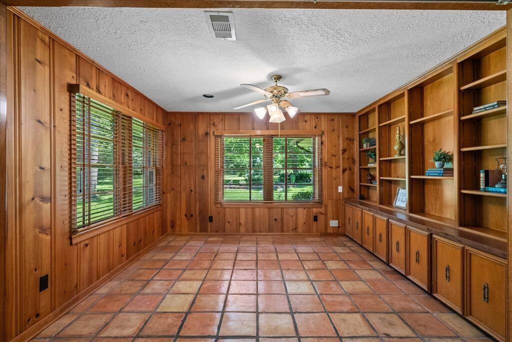 The knotty pine paneling in the den or home office evokes a sense of nostalgia, while providing a charming space ideal for transforming into a library, study, or home office.