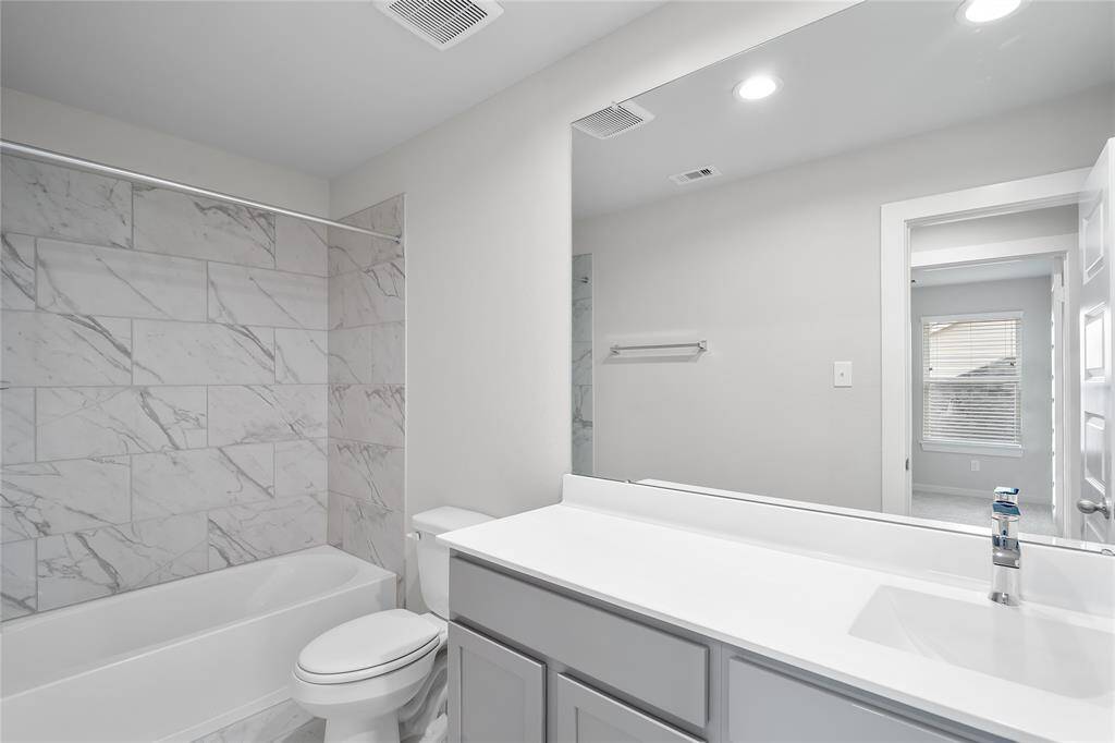 Secondary bedroom features plush carpet, neutral paint, lighting and a large window with privacy blinds.