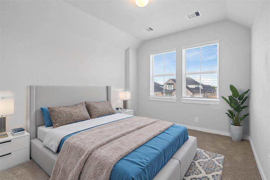 Secondary bedroom features plush carpet, neutral paint, lighting and a large window with privacy blinds.