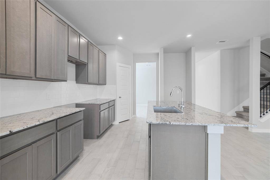 This stunning kitchen displays such beautiful stained cabinets, custom neutral paint, granite countertops, modern backsplash, oversized kitchen island with extra storage, breakfast bar, recessed lighting, high ceilings and walk in pantry.