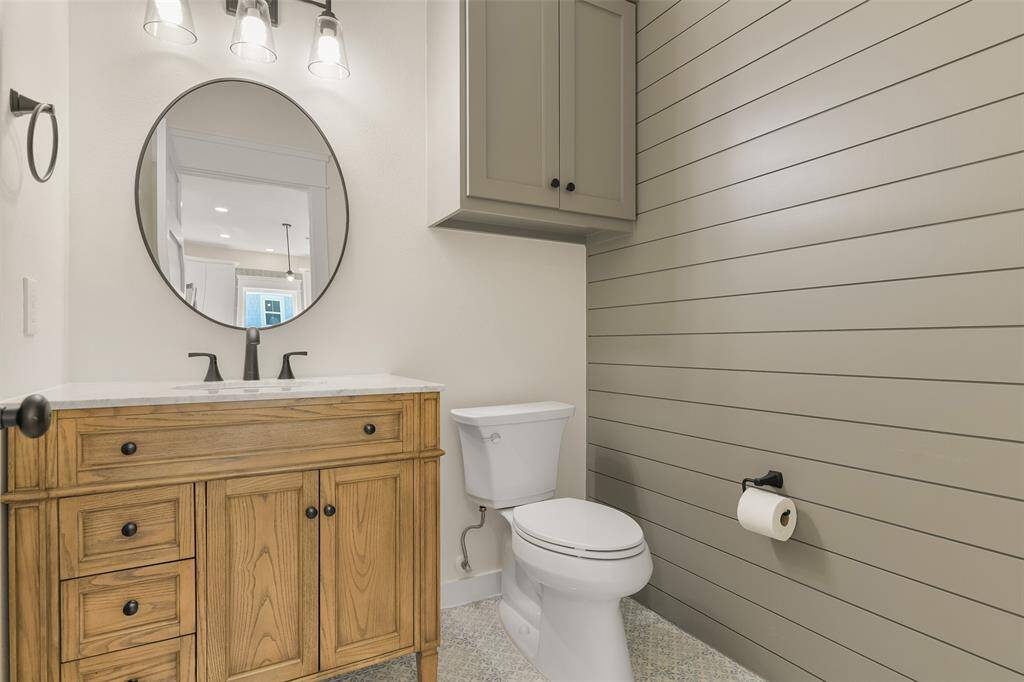Charming third-floor half bath featuring stylish shiplap walls, seamlessly blending elegance with convenience.