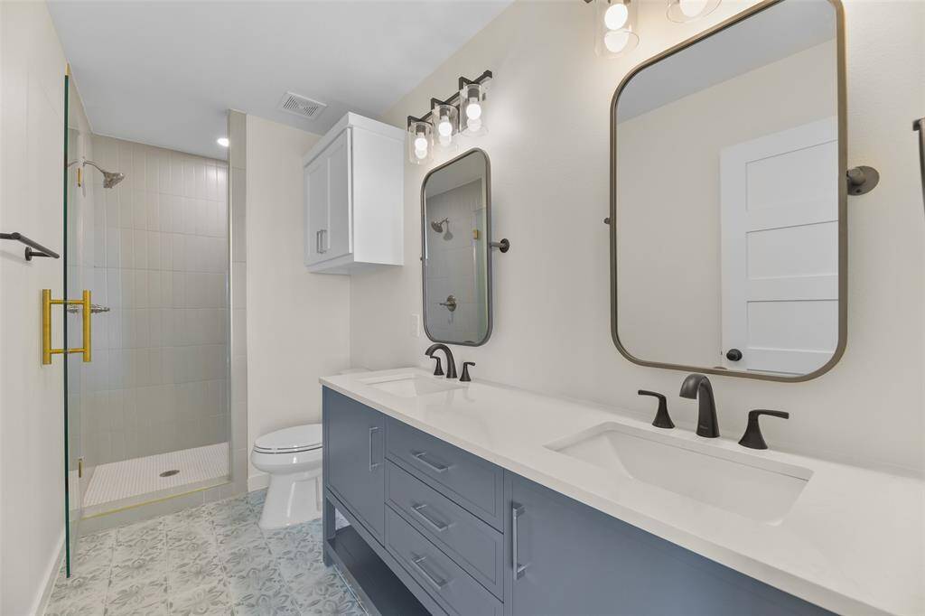 The double vanity and walk-in shower have custom tile work.