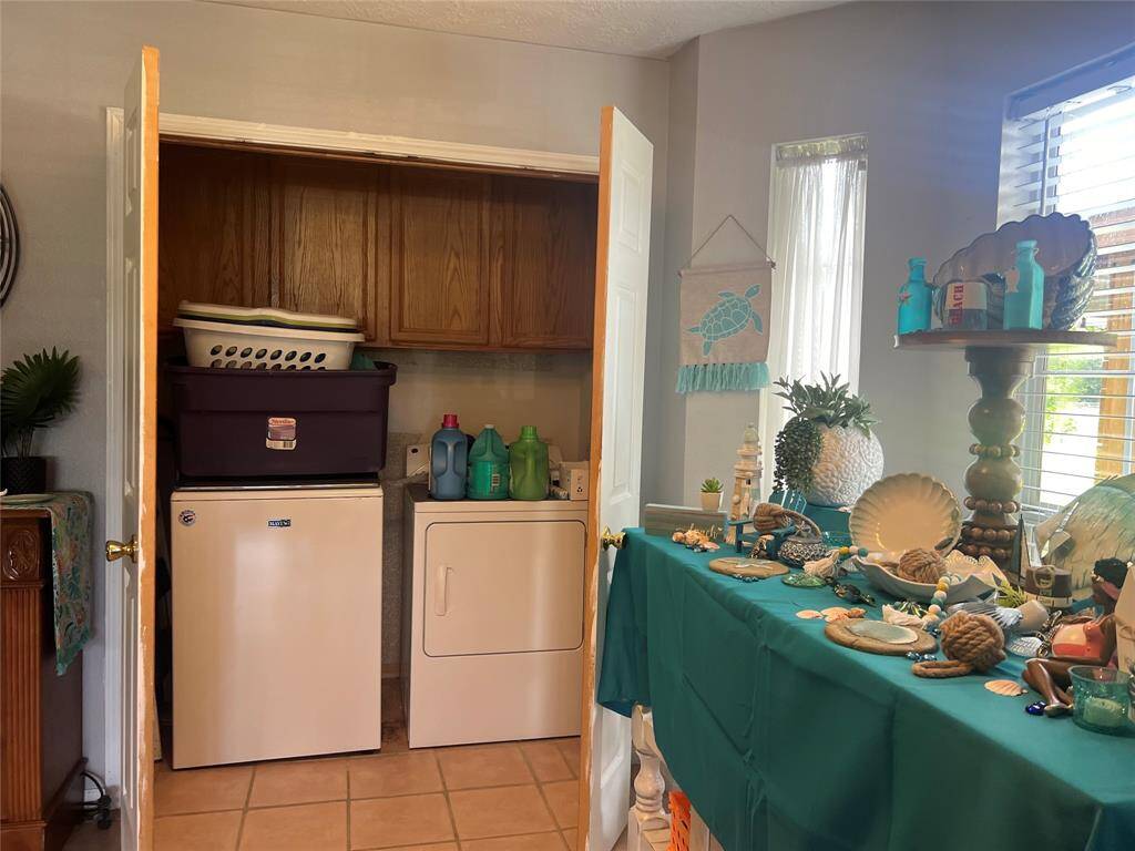 The  cozy kitchen corner area has a compact dishwasher, a  washer and dryer, and ample cabinet space above. The dining area has a sea-themed decor with a view of the window allowing natural light.