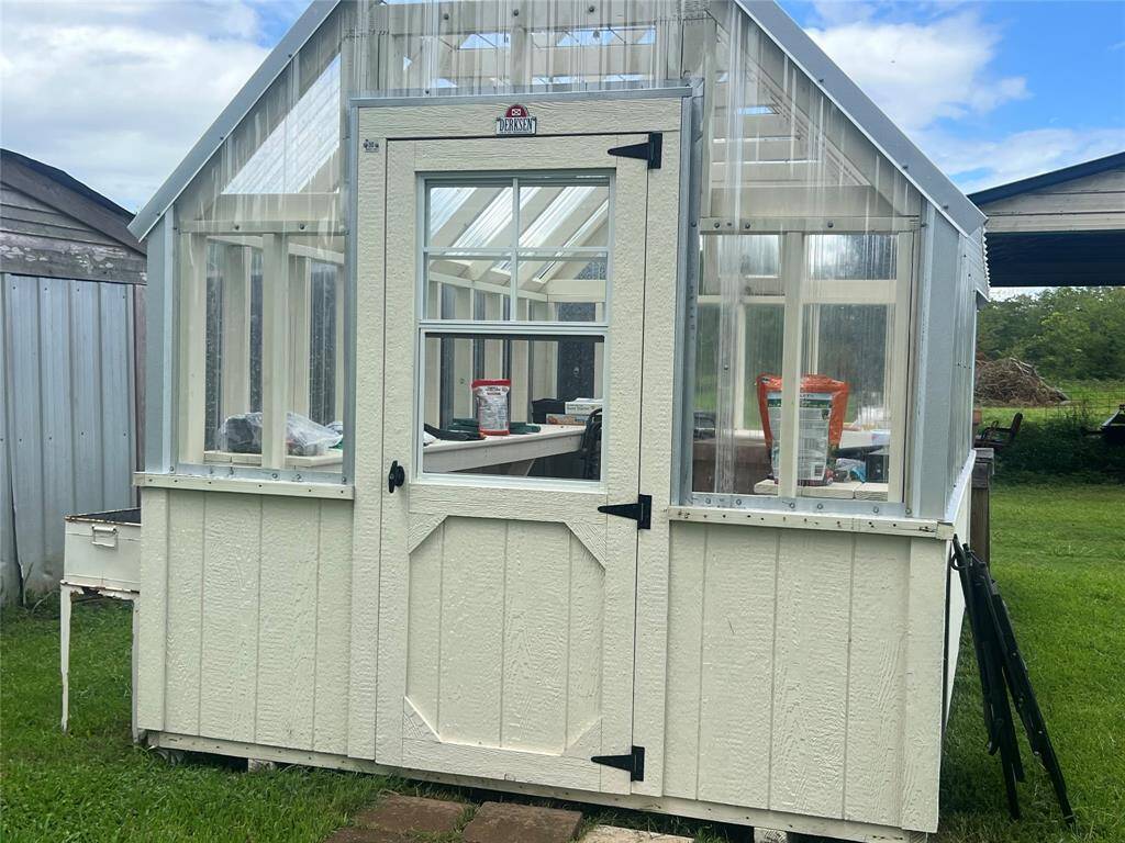 This is a quaint, freestanding greenhouse with a white exterior and clear panels, perfect for gardening enthusiasts looking to cultivate plants year-round. Owner is taking it.