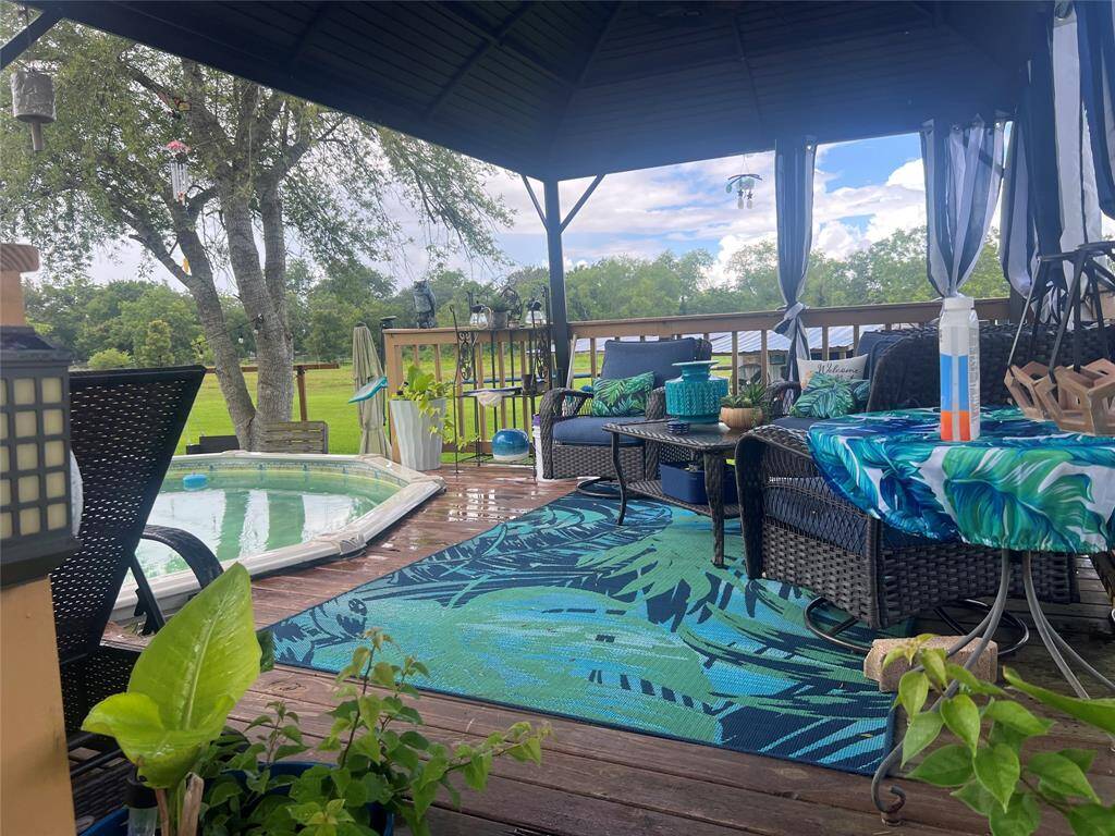Jus relax in this outdoor living space with a covered deck, comfortable patio furniture, and an inviting above-ground pool. The setting is surrounded by greenery, offering a private and serene backyard oasis.