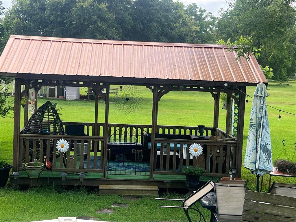 This charming wooden gazebo with a rustic corrugated metal roof, providing a cozy outdoor space for relaxation and entertainment. The surrounding green lawn adds to the tranquil backyard setting.