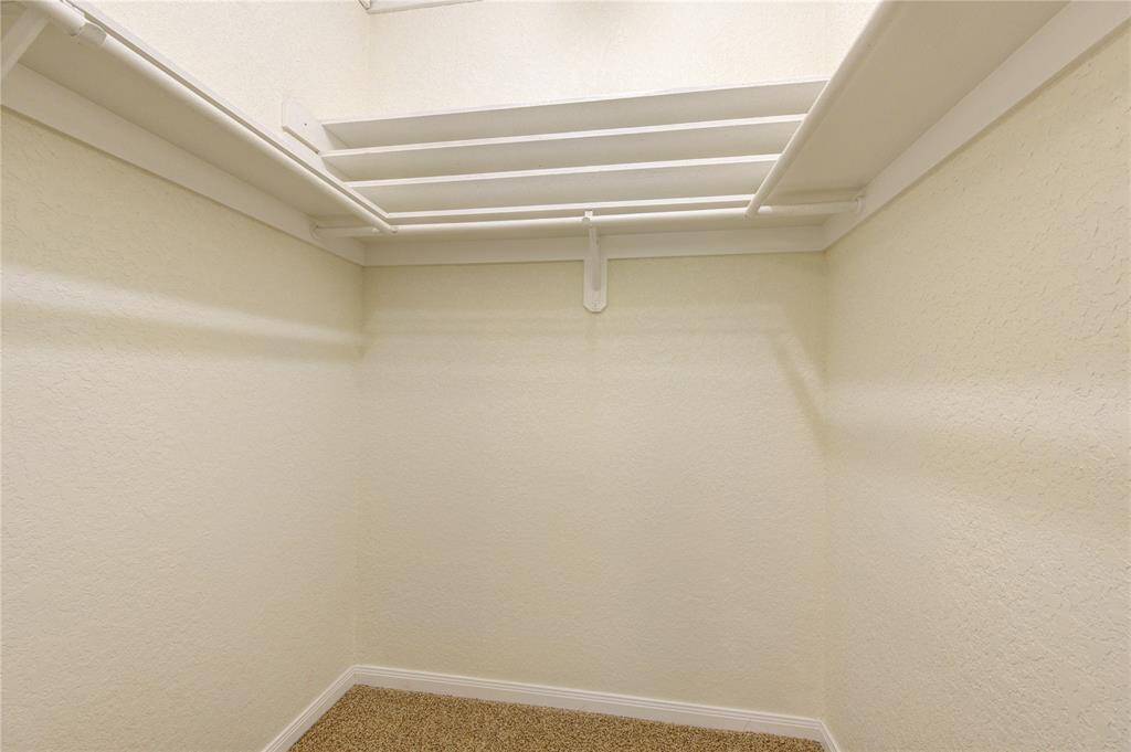 Primary closet with built-in shelving offering ample storage space.