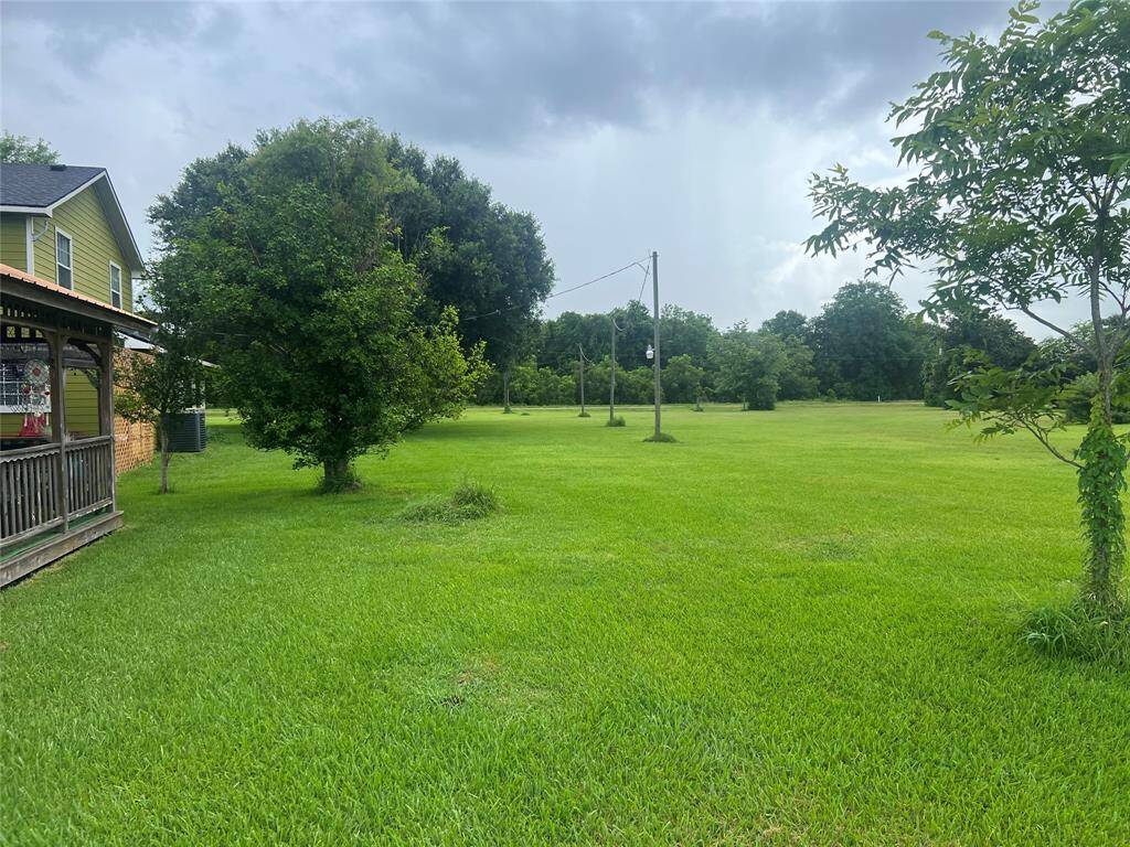 This is spacious and well-maintained lawn adjacent to a charming two-story house with a cozy porch. The property features lush greenery and mature trees, offering a serene outdoor space.