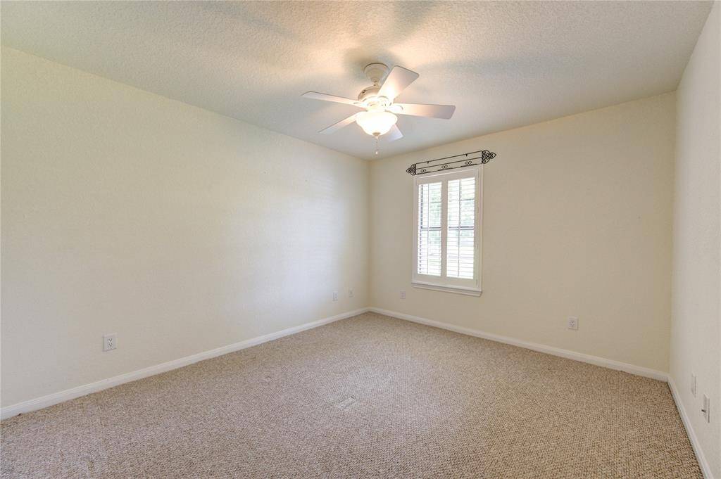 Guest room with ceiling fan, a single window with blinds, and plush carpeting.