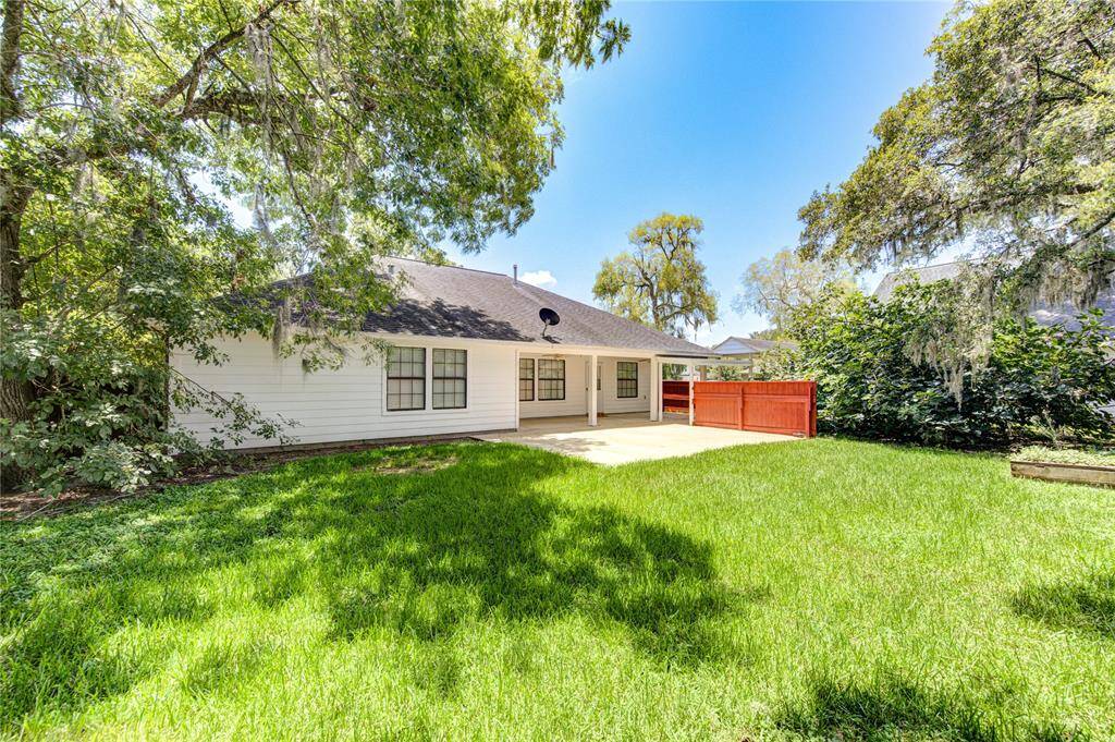 View of back of home from back yard with gorgeous trees, offering both shade and privacy.