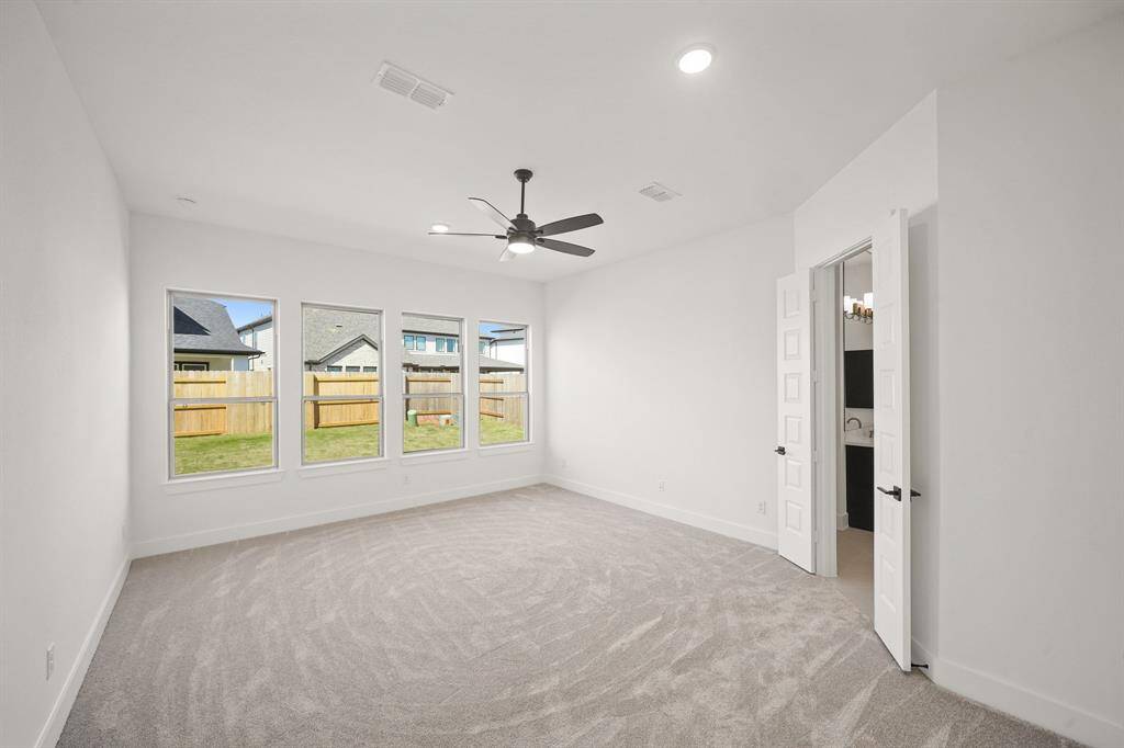 The primary bedroom is expansive, with high ceilings, large windows letting in ample light, and a calming, modern design that creates a serene retreat.
