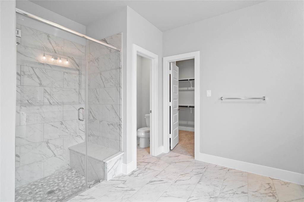 This additional view of the primary bath showcased the large walk-in shower with tile surround, privacy toilet area, and spacious walk-in closet.