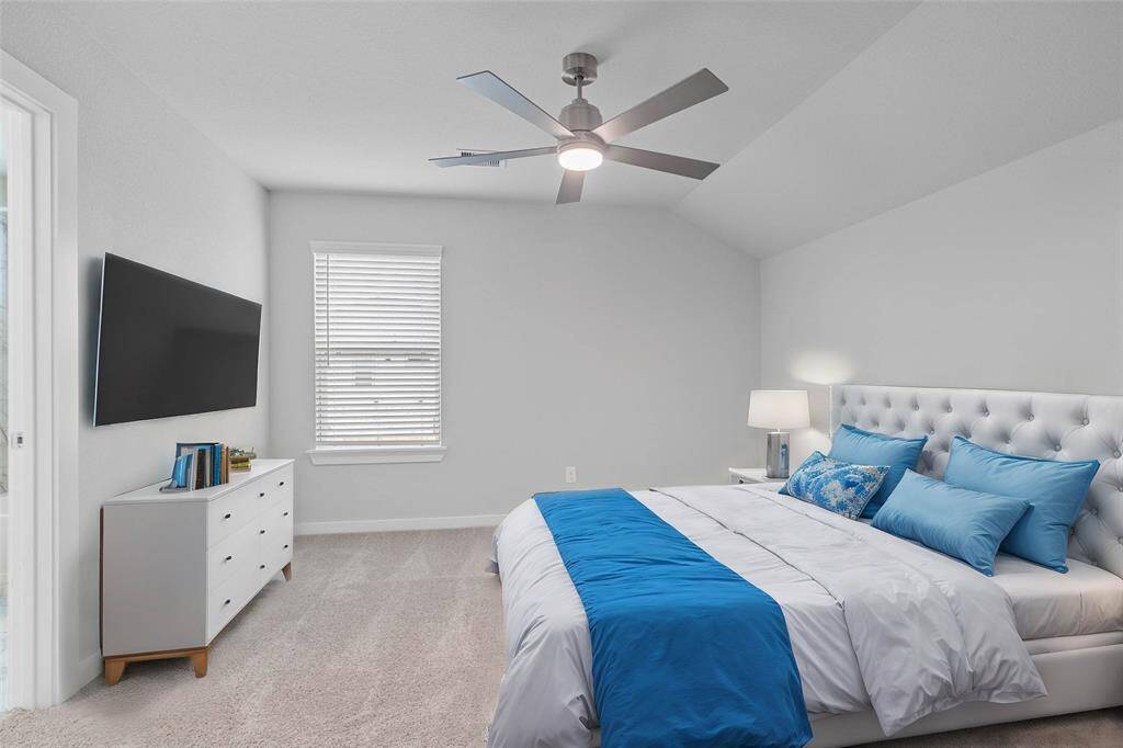 Secondary bedroom features plush carpet, custom paint, ceiling fan with lighting and a large window with privacy blinds.