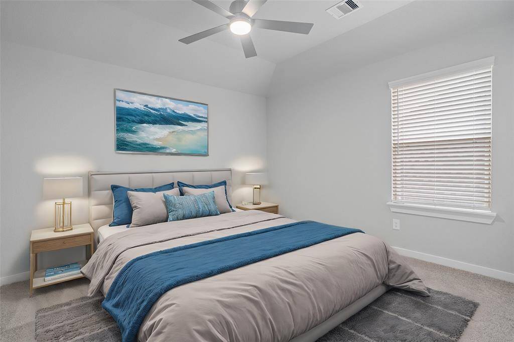 Secondary bedroom features plush carpet, custom paint, ceiling fan with lighting and a large window with privacy blinds.