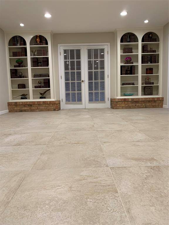 Beautiful twin built-in bookshelves frame French doors leading to the covered patio.