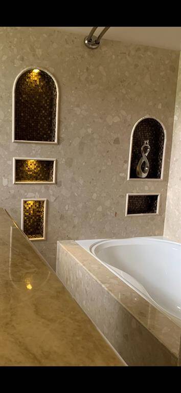 Custom tile treatments surround the soaking tub in the guest bathroom.